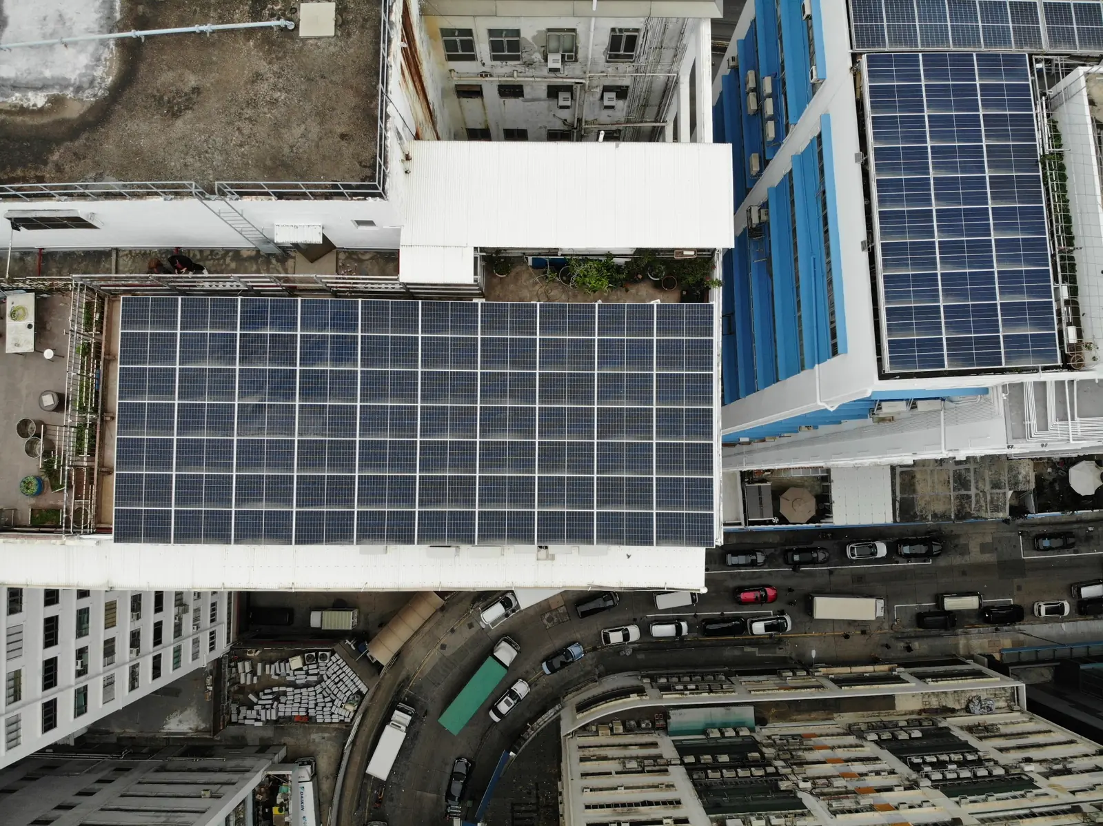 市區工業樓宇平頂鋪設多組太陽能板的垂直航拍照片。