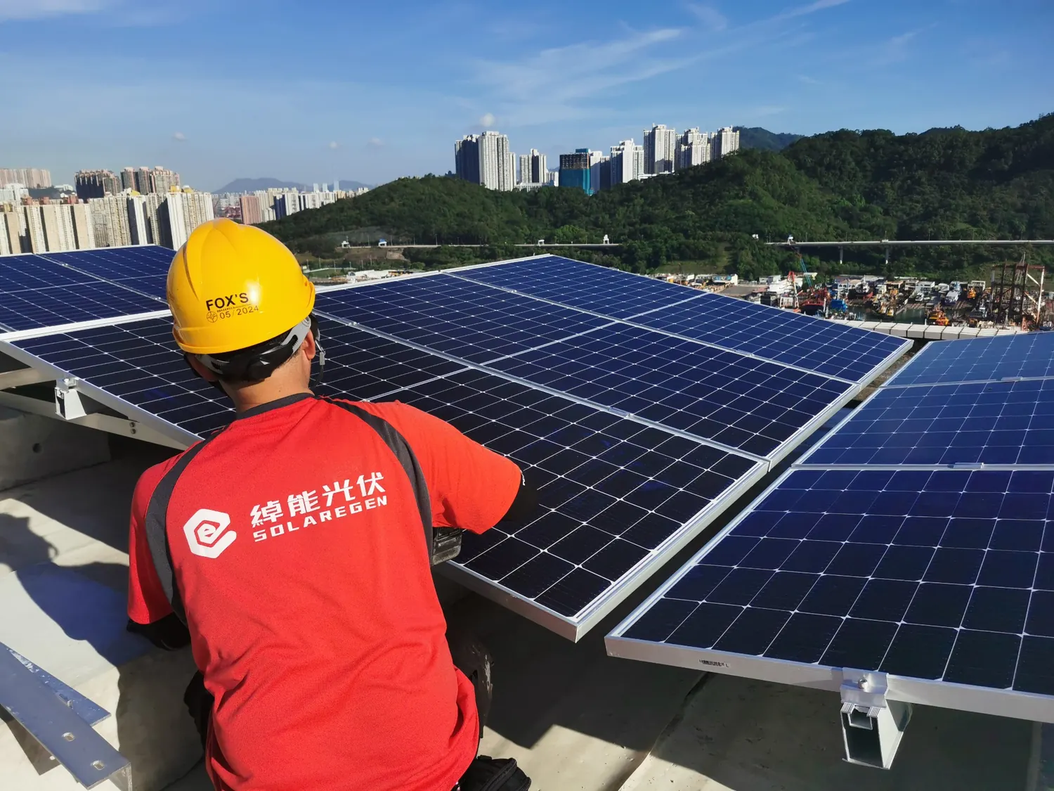 身穿紅色綽能光伏工作服的人員在太陽能板旁。